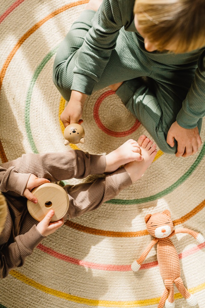 Children playing with wooden toys on a colorful rug