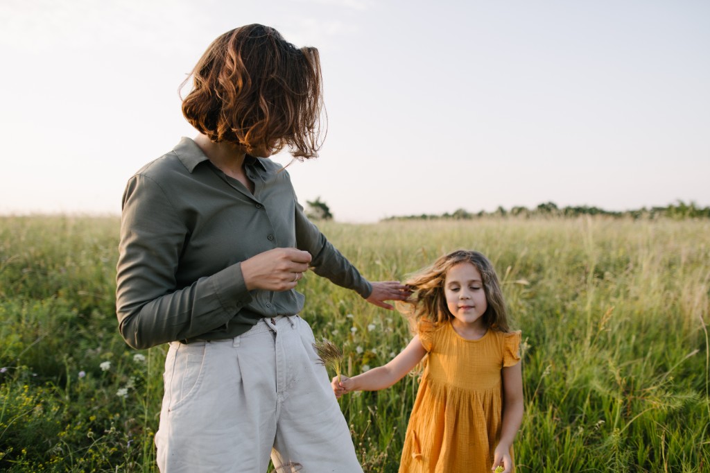 Mother and daughter walking together through a sunlit field