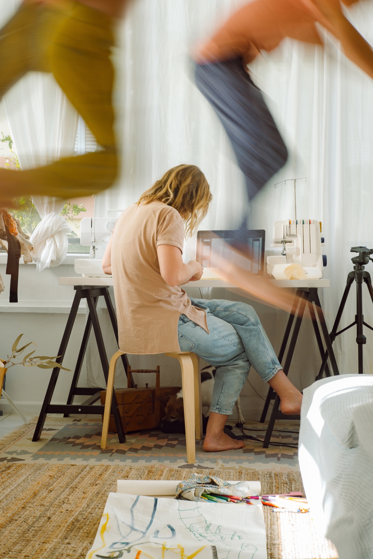 Parent working at a laptop while children play nearby